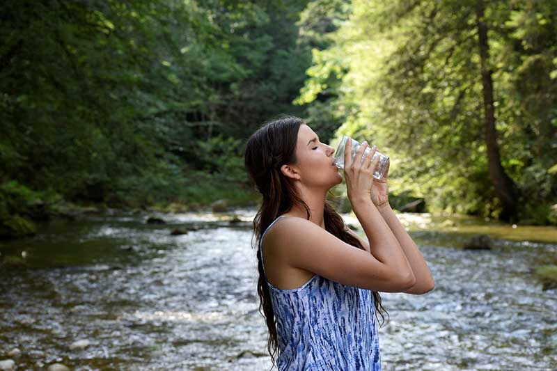 Frau trinkt Wasser am Fluß
